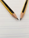 Two sharpened pencil over a ruled white paper Royalty Free Stock Photo