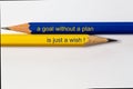 Two sharpened pencils in blue and yellow point in different directions isolated against a white background with the phrase: a goal Royalty Free Stock Photo