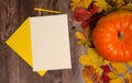 Two sheets of blank paper, a pumpkin, colorful leaves, a pen on a wooden background. Royalty Free Stock Photo