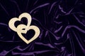 Two shiny gold hearts on a purple velvet background. Valentine`s day concept Royalty Free Stock Photo