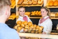 Two shopkeepers presenting a basket with buns to client Royalty Free Stock Photo