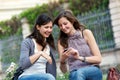Two shopping girls in park with a mobile phone