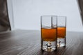 Two shot glasses with whiskey on a wooden background table next to window. Space for text Royalty Free Stock Photo