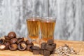 Two shot of home-brewed whiskey stand on a wooden board