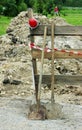 two shovels, a red lamp to the fence, enclosing ditch buried in the ground. Royalty Free Stock Photo