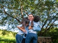 Two sibling little girls with mom laughing and hugging each other on warm and sunny summer day in the garden. Young girls with her Royalty Free Stock Photo