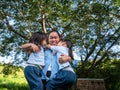 Two sibling little girls with mom laughing and hugging each other on warm and sunny summer day in the garden. Young girls with her Royalty Free Stock Photo