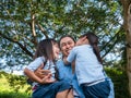 Two sibling little girls with mom laughing and hugging each other on warm and sunny summer day in the garden. Young girls with her Royalty Free Stock Photo