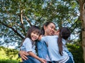 Two sibling little girls with mom laughing and hugging each other on warm and sunny summer day in the garden. Young girls with her Royalty Free Stock Photo