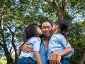 Two sibling little girls with mom laughing and hugging each other on warm and sunny summer day in the garden. Young girls with her Royalty Free Stock Photo