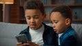 Two siblings African American brothers sons children boys friends little kids at home using mobile phone without Royalty Free Stock Photo