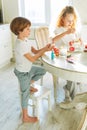 Two siblings brother and sister toddler boy tween girl painting easter eggs on kitchen at home on the spring sunny day Royalty Free Stock Photo