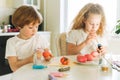 Two siblings brother and sister toddler boy tween girl painting easter eggs on kitchen at home on spring sunny day Royalty Free Stock Photo