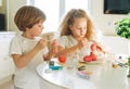 Two siblings brother and sister toddler boy tween girl painting easter eggs on kitchen at home on the spring sunny day Royalty Free Stock Photo
