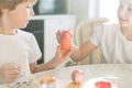 Two siblings brother and sister toddler boy tween girl painting easter eggs on kitchen at home on spring sunny day Royalty Free Stock Photo