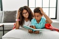 Two siblings lying on the sofa reading a book confuse and wondering about question