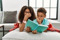 Two siblings lying on the sofa reading a book smelling something stinky and disgusting, intolerable smell, holding breath with