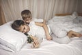 Two siblings watching video in mobile electronic device in the bed, gadget addiction, lifestyle Royalty Free Stock Photo