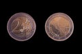 Two sides of the 2 euro coin placed side-by-side on black background