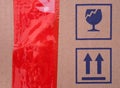 Two signs on cardboard box - Fragile and This Way Up and a red scotch tape on cardboard Royalty Free Stock Photo