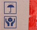 Two signs on cardboard box - Umbrella and Handle with Care, and red scotch tape on cardboard Royalty Free Stock Photo