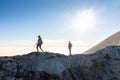 Two silhouettes, hikers on the walk, sky with plane contrails and sun