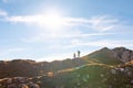 Two silhouettes, hikers on the walk, sky with plane contrails and sun