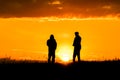 Two silhouettes of men talking at sunset or sunrise with dramatic sky and clouds.Dialogue and meeting two people on the horizon