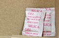 Two Silica gel packets in the bottom corner of a cardboard box.