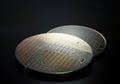 Two silicon wafers showcasing intricate microchip patterns on a dark background Royalty Free Stock Photo