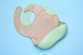 Two silicone baby bibs on light blue background, top view. First food