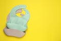 Two silicone baby bibs on yellow background, top view. Space for text Royalty Free Stock Photo