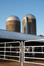 The two silos are much taller than the barn. There is a gate in front to keep the cows from running away.