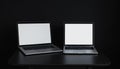 Two silver laptops with white screens side by side on a dark desk Royalty Free Stock Photo