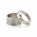 Two silver rings with distinct textures. The left ring is wider with a pebble-like pattern, Royalty Free Stock Photo