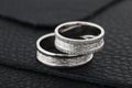 Two silver wedding rings on black leather background