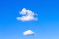 Two single clouds float on blue sky