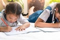Two sister girl writes to writing-books. The decision of lessons. girl lay down drawing the picture Royalty Free Stock Photo