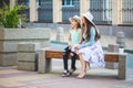 Two sisters, a beautiful brunette girl and a young girl walking in the city, sitting on a bench and talking, laughing Royalty Free Stock Photo