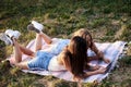 Two sisters, blowing soap bubbles in park, Young pretty girls, wearing jeans shorts, green khaki beige tops, having fun outside. Royalty Free Stock Photo