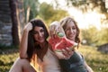 Two sisters, blowing soap bubbles in park, Young pretty girls, wearing jeans shorts, green khaki beige tops, having fun outside. Royalty Free Stock Photo