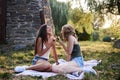 Two sisters, blowing soap bubbles in park, Young pretty girls, wearing jeans shorts, green khaki beige tops, having fun outside. Royalty Free Stock Photo