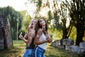 Two sisters, blowing soap bubbles in park, Young pretty girls, wearing jeans shorts, green khaki beige tops, having fun outside. Royalty Free Stock Photo