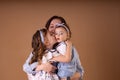 Two sisters in blue outfit kiss in arms of mother