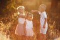 two sisters and brother are playing, hugging in the field on summer. children playing outdoors and smiling on sunset Royalty Free Stock Photo