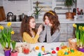 Two sisters in bunny ears painting eggs on the kitchen. Happy family preparing for Easter Royalty Free Stock Photo