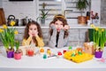 Two sisters in bunny ears painting eggs on the kitchen. Happy family preparing for Easter Royalty Free Stock Photo