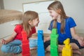 Two sisters in a children`s room build towers from multi-colored cubes. They are laughing Royalty Free Stock Photo