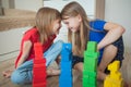 Two sisters in a children`s room build towers from multi-colored cubes. They are laughing Royalty Free Stock Photo
