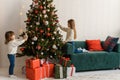 Two sisters decorate the Christmas tree. Cute little girls are getting ready for Christmas in the morning. Royalty Free Stock Photo